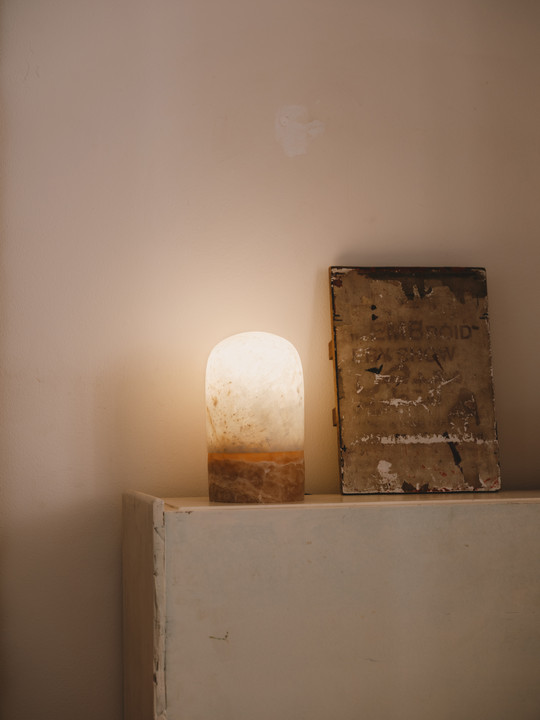 Stenlampe lyser på skab ved siden af bog.