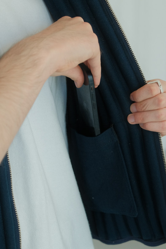 Person placing a smartphone in an inner pocket of the vest.