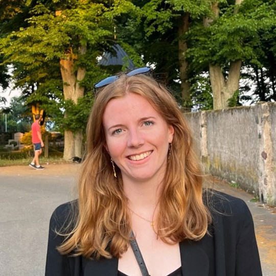 Photo of Emilie Hauge with trees behind. The hair is red and a bit longer than shoulder-length.
