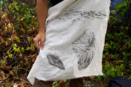 Person holding white fabric with black prints of rocks and natural textures.