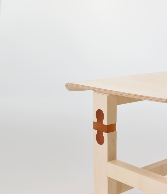 Close-up of light wooden furniture with a brown key-shaped joint in the leg.