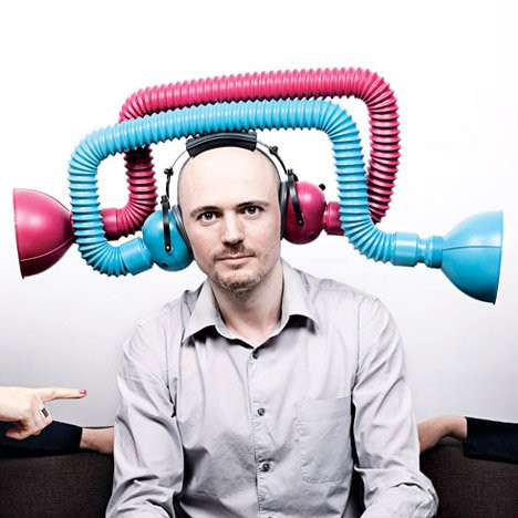 Man wearing ear defenders surrounded by flexible blue and pink tubes.