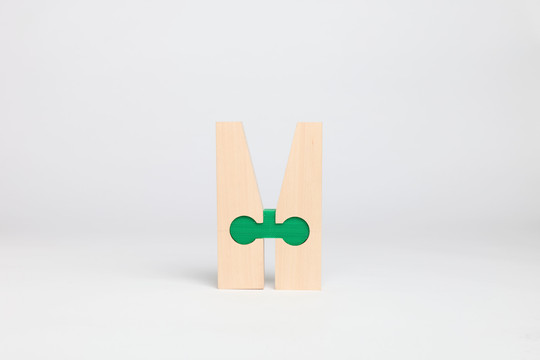 Two wooden parts joined by a green key-shaped connector.