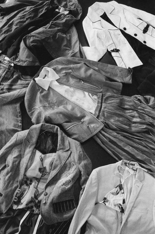 Assorted jackets, shirts and trousers arranged in an overlapping composition.
