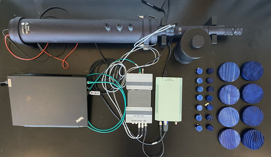 Technical equipment, cables and blue wooden discs arranged on a black surface.