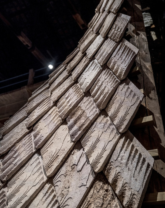 Close-up of overlapping, rough-textured panels with grooved surfaces on a curved structure.