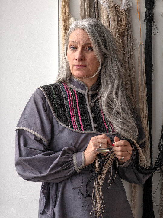 Female researcher in grey dress standing in front of wall of yarn samples