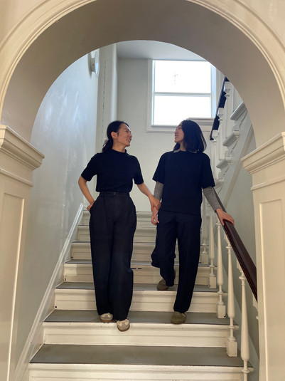 Two people on a curved staircase in a bright stairwell, seen through a round opening.