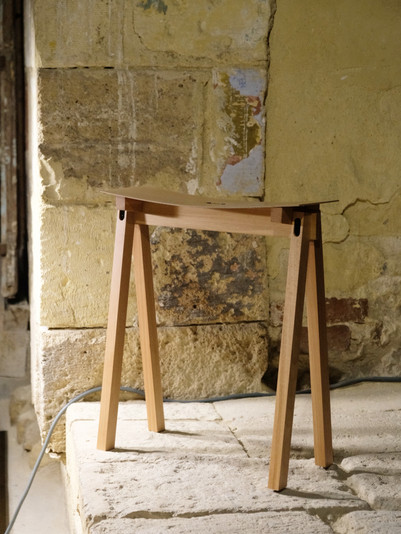 Wooden stool against a textured stone wall