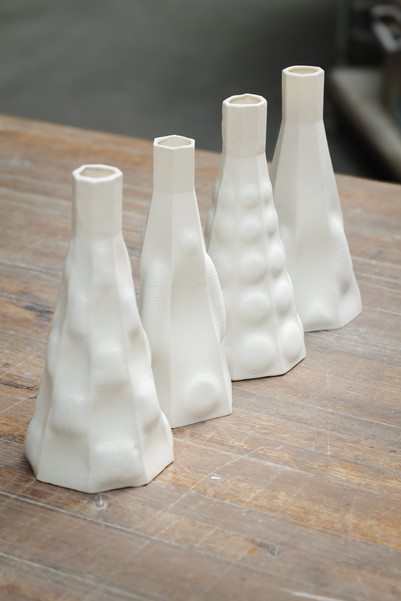 Four white ceramic vessels with textured surfaces on a wooden table.