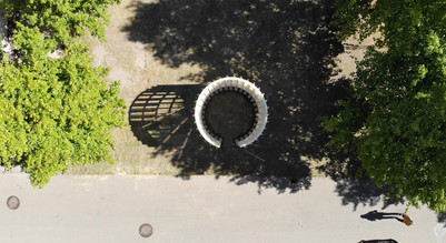 Aerial view of a circular wooden pavilion among large trees.