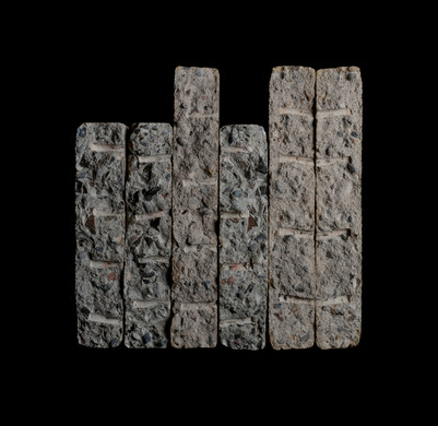 Six elongated concrete samples with exposed aggregate and grooved surfaces on black.