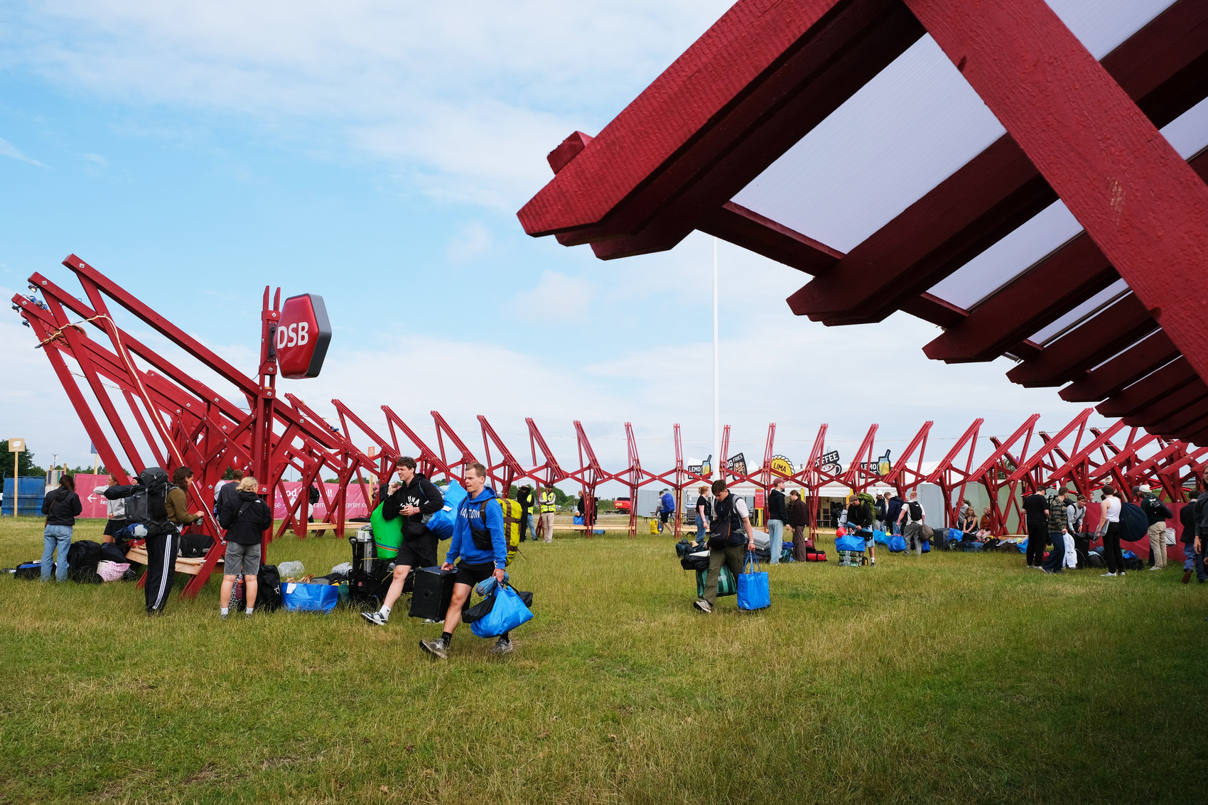 Red support beams in a circular structure. Festival guests are arriving