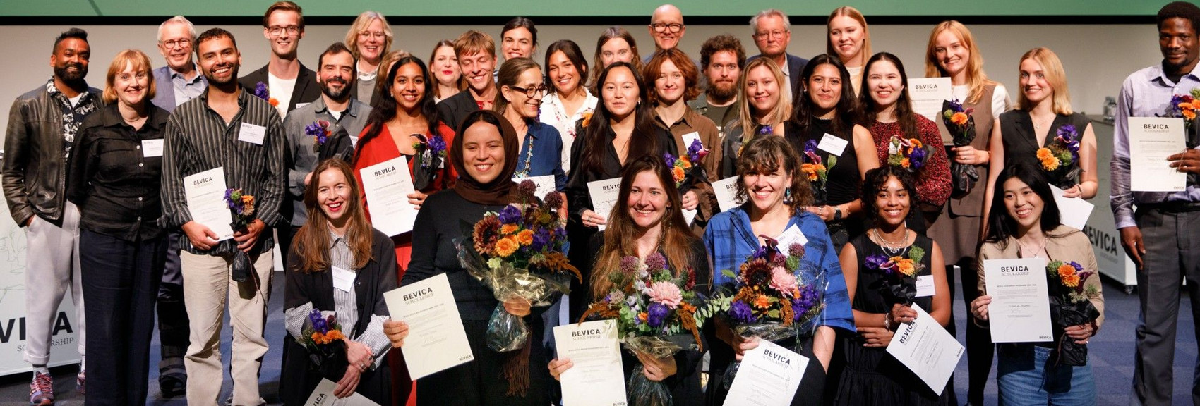 Groups of people holding diplomas in front of a banner with the text “Bevica Scholarship.”