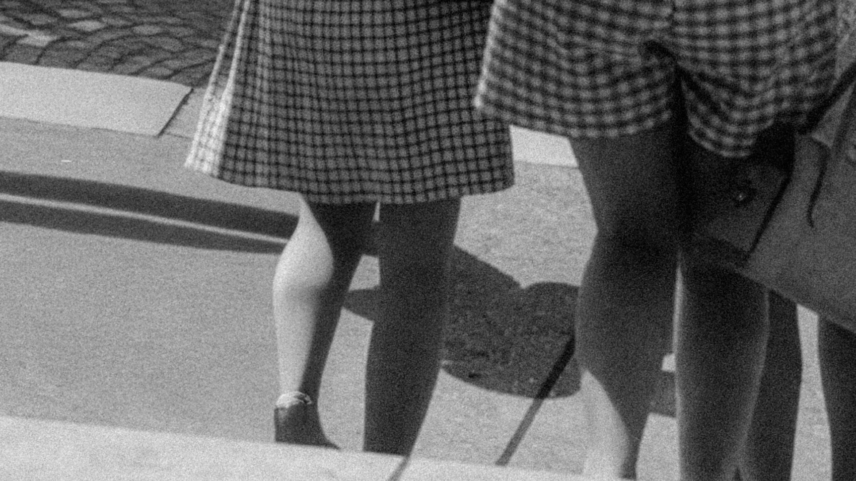 black and white archive photo of two women walking down a flight of stairs wearing checkered clothes.