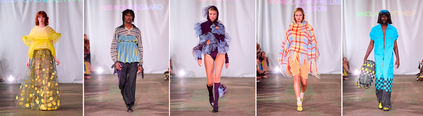 Five runway models wear experimental fashion designs: a sheer yellow dress, a layered blue-striped outfit, a purple bodysuit with large blue tulle ruffles, and a colorful fringed knit ensemble.